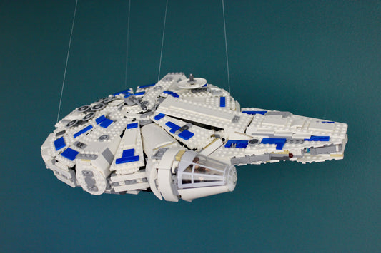LEGO Millennium Falcon hanging from the ceiling mount by four adjustable lines against a teal wall