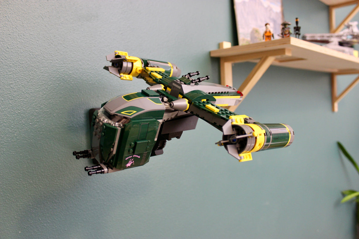 LEGO Star Wars Bounty Hunter Assault Gunship 7930 on its black wall mount against a teal wall, below a wooden shelf
