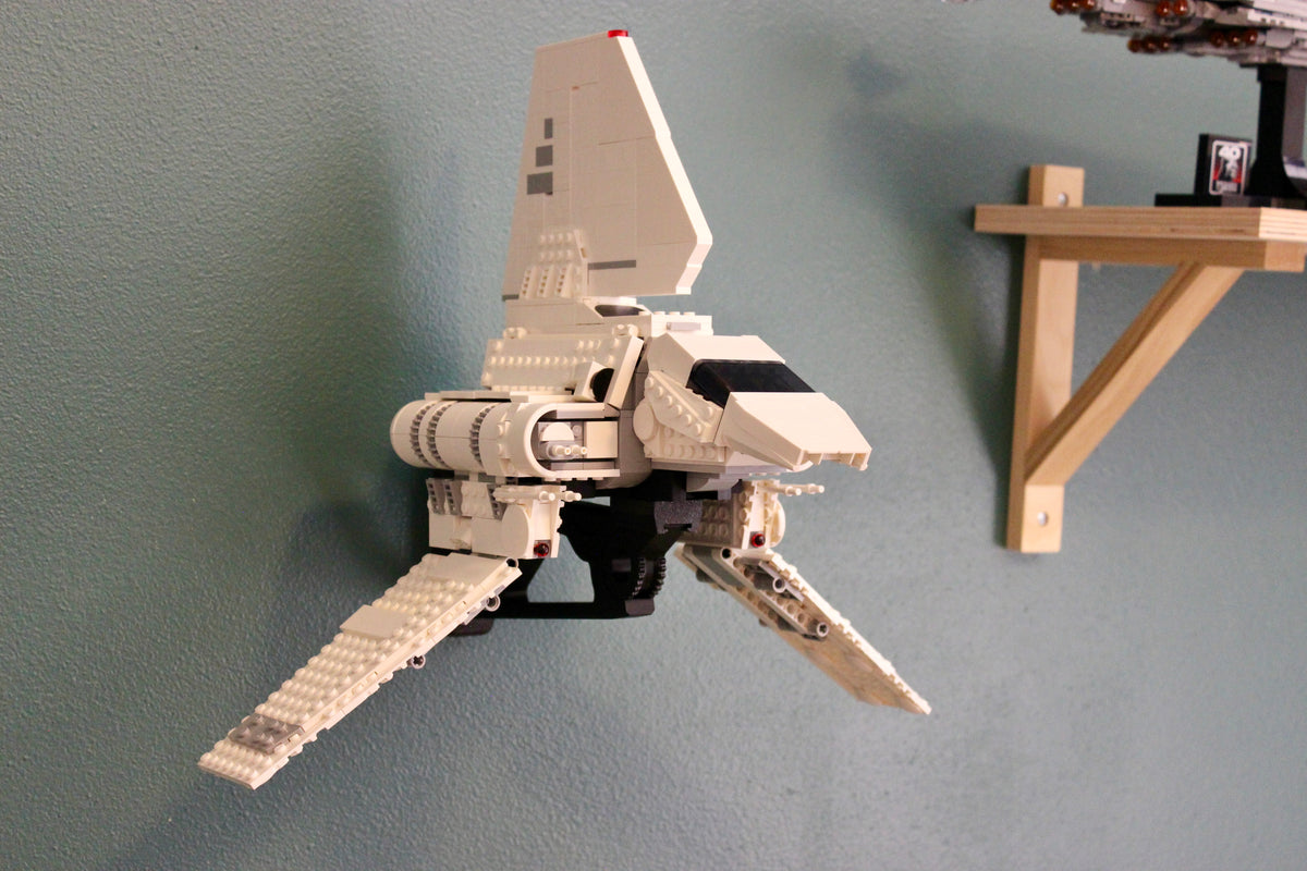 LEGO Star Wars Imperial Lambda-Class Shuttle 75459 on its black wall mount against a teal wall, beside a wooden shelf