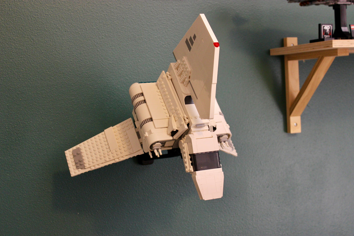 LEGO Imperial Lambda-Class Shuttle 75459 tilted nose-down on its wall mount beside a wooden shelf