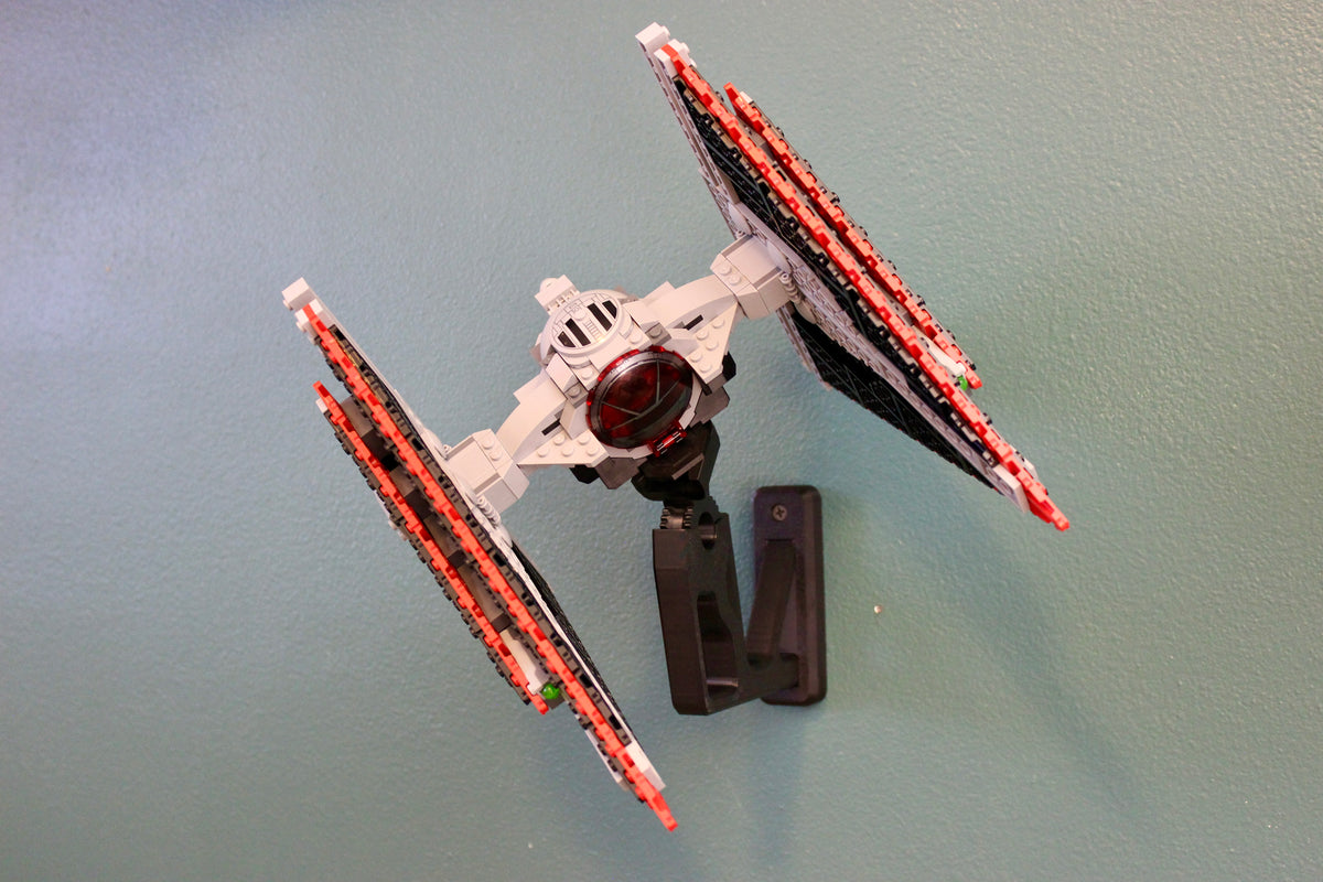 LEGO Star Wars Sith TIE Fighter 75272 on its black wall mount against a teal wall, angled view