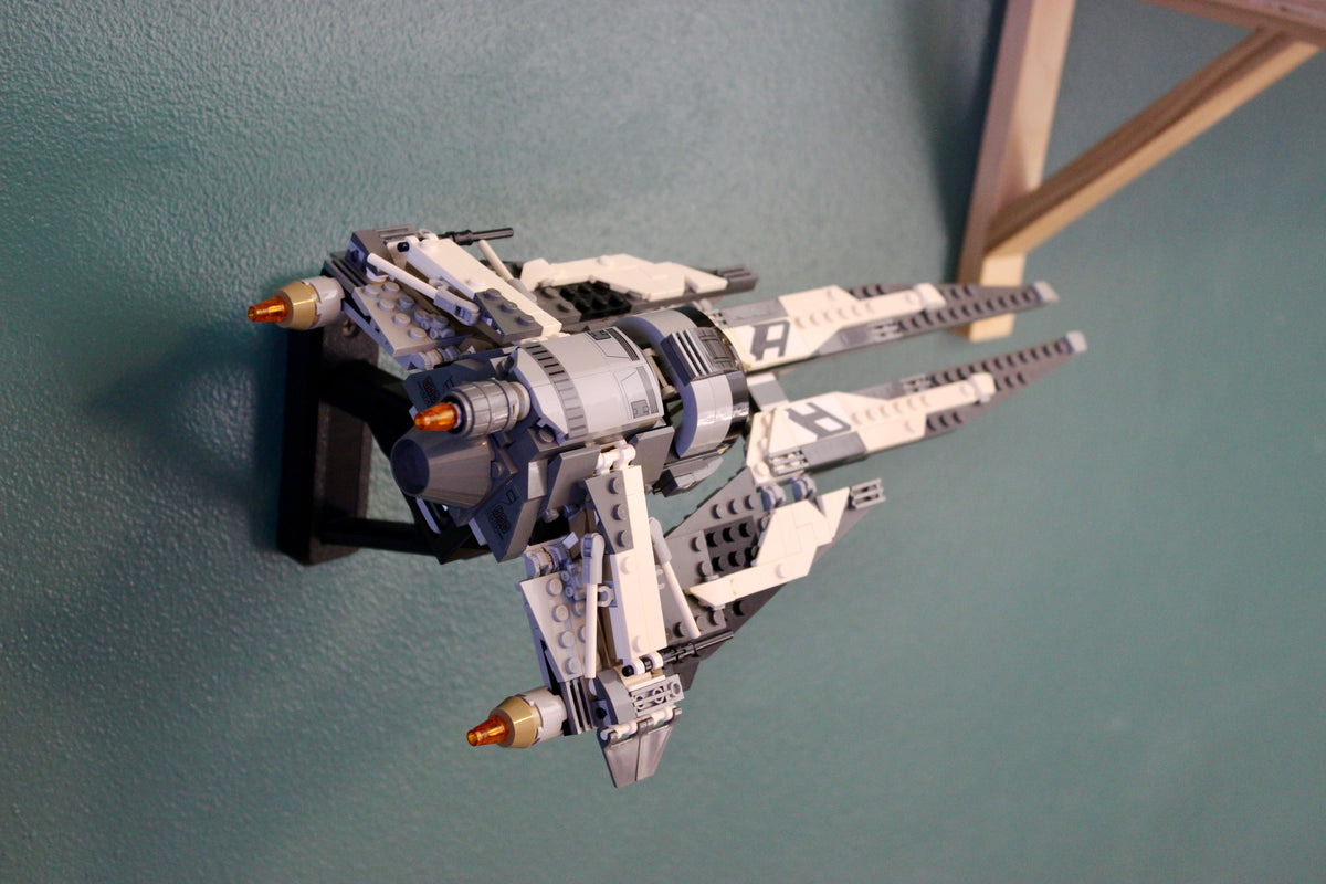 LEGO Black Ace TIE Interceptor 75242 seen from below on its wall mount, next to a wooden shelf bracket