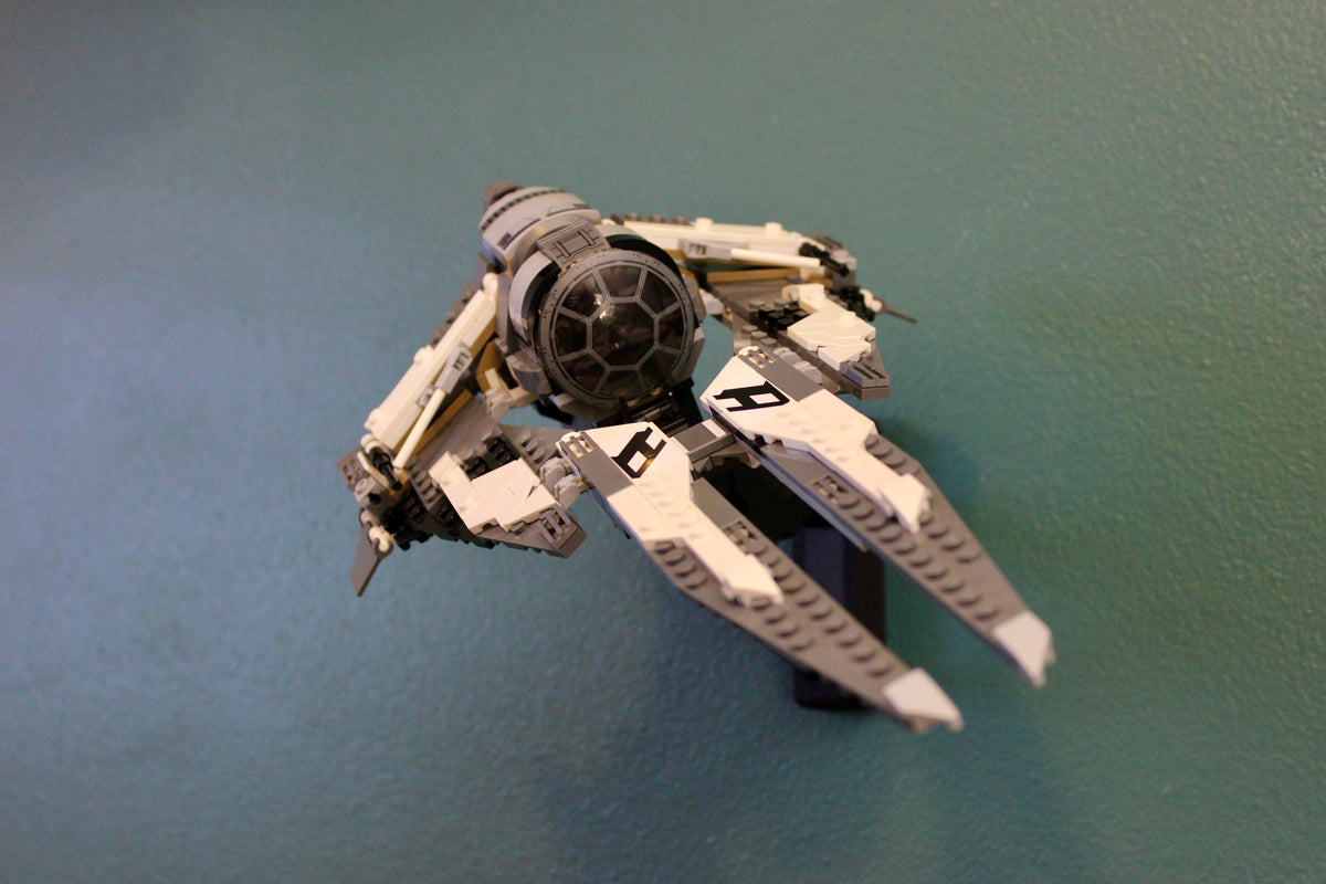 LEGO Star Wars Black Ace TIE Interceptor 75242 on its black wall mount against a teal wall, angled from above