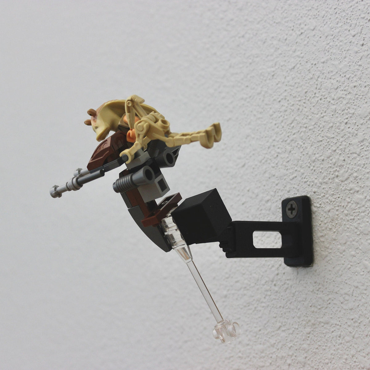 Small LEGO build tilted on the short black universal wall mount against a white wall