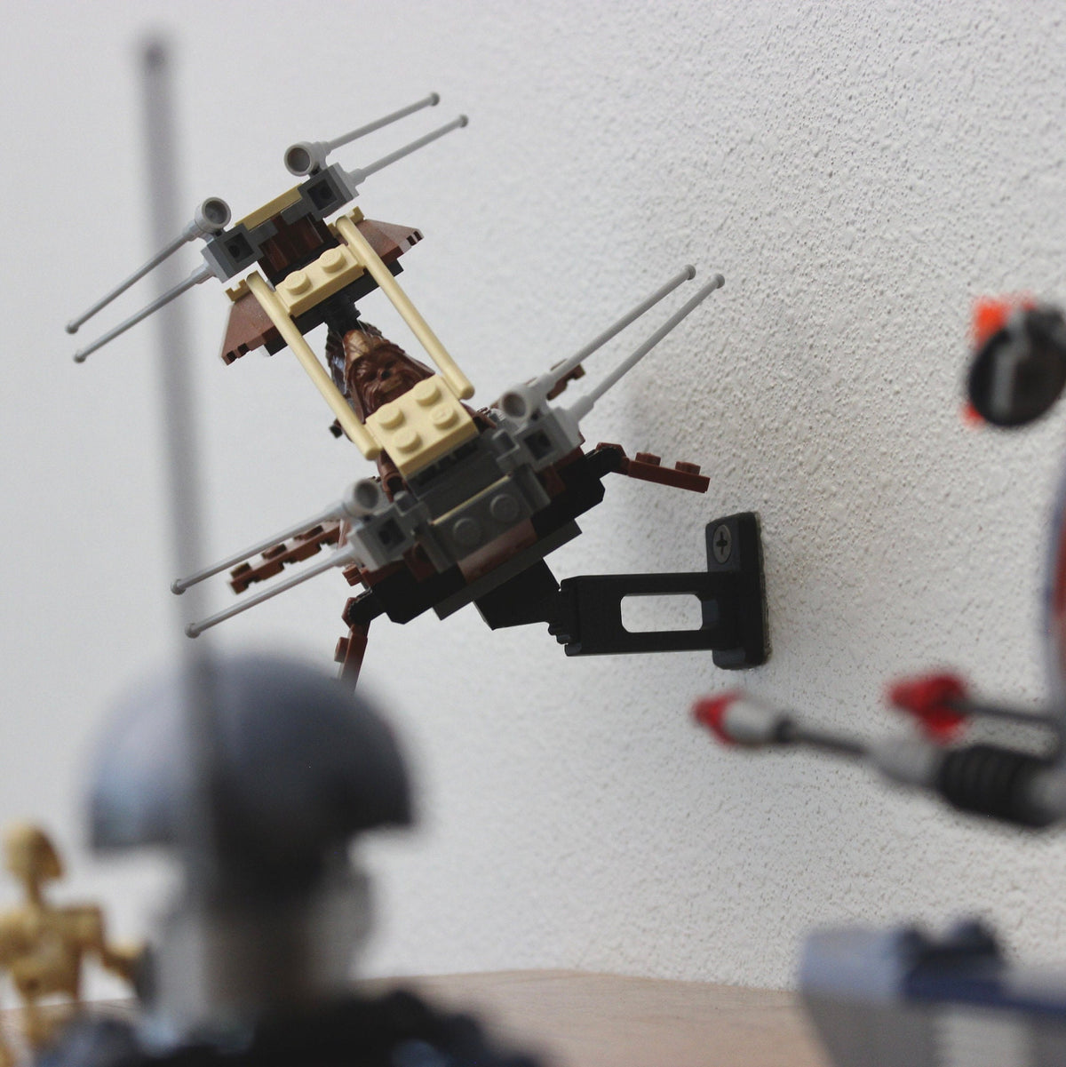 Small LEGO Star Wars ship angled on the short black universal wall mount among other displays