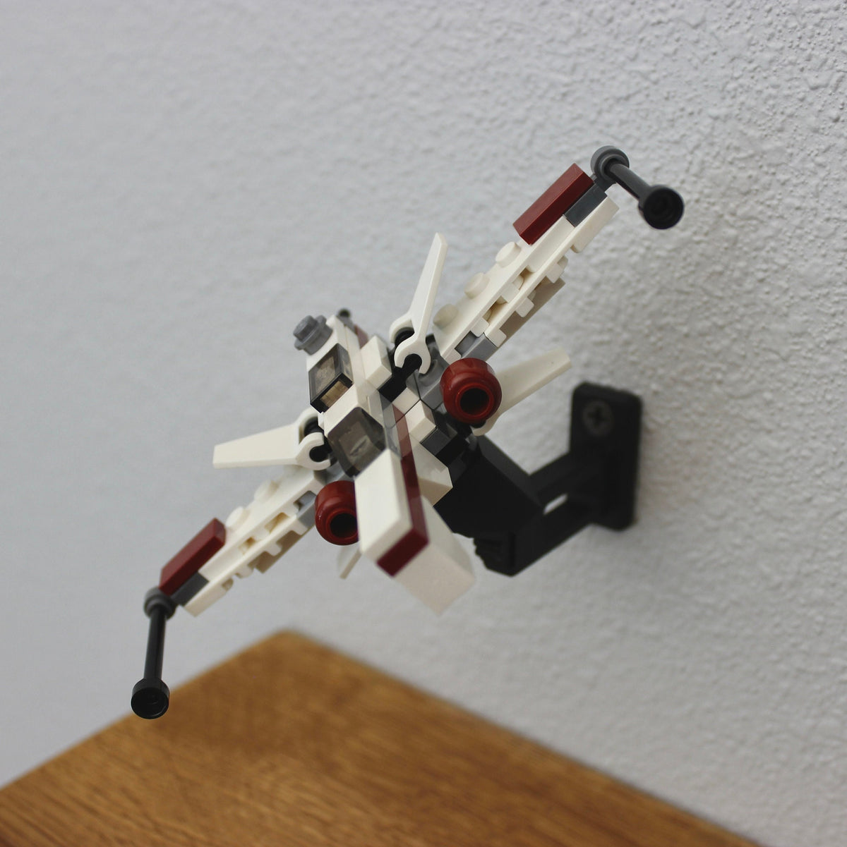 Small LEGO Star Wars starfighter tilted upward on the short black universal wall mount