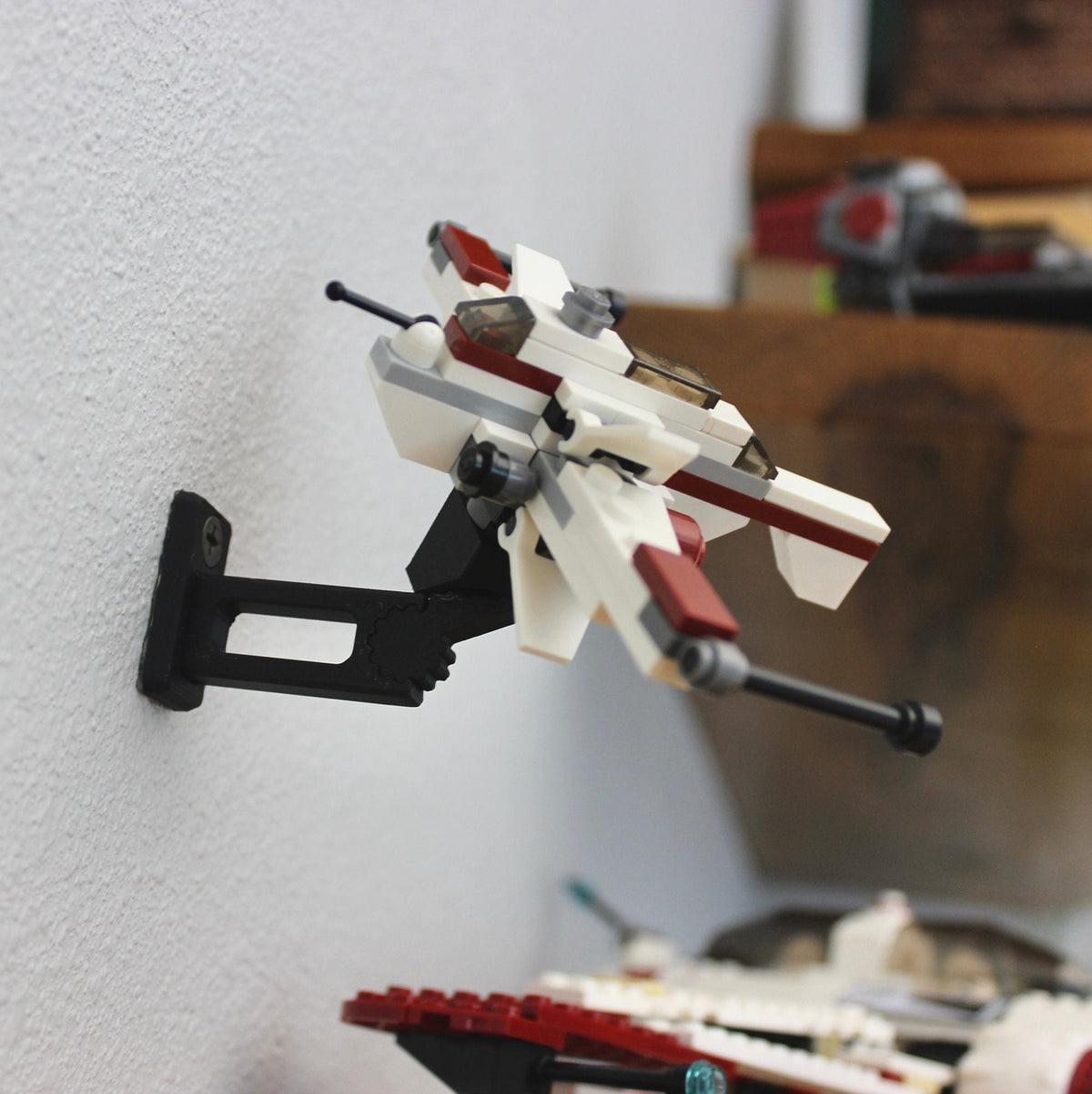 Small LEGO Star Wars ship held at an angle by the short black universal wall mount
