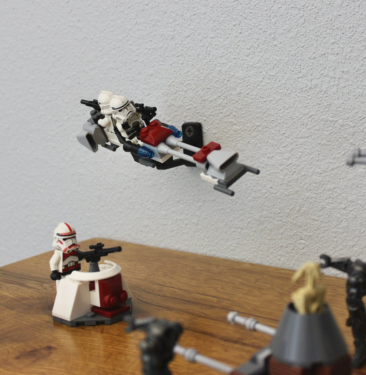 Small LEGO speeder and minifigures displayed on the short black universal wall mount over a wooden shelf