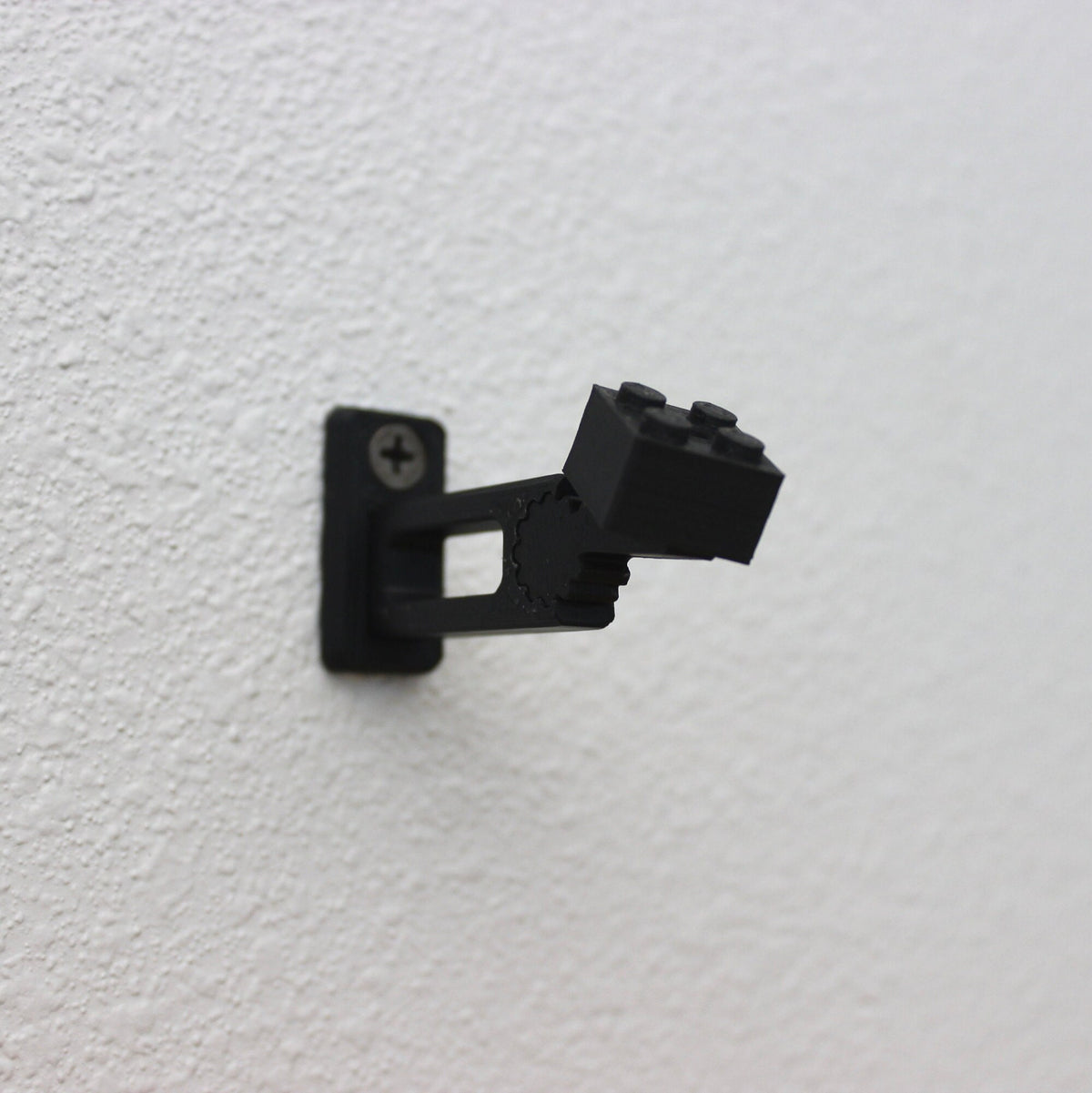 Empty short black universal wall mount fixed to a white wall