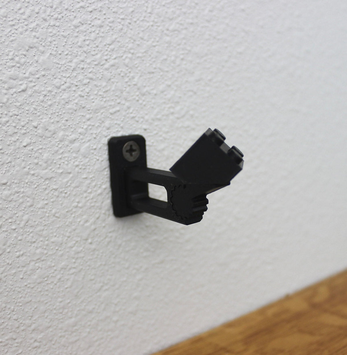 Short black universal wall mount on a white wall, seen from the side