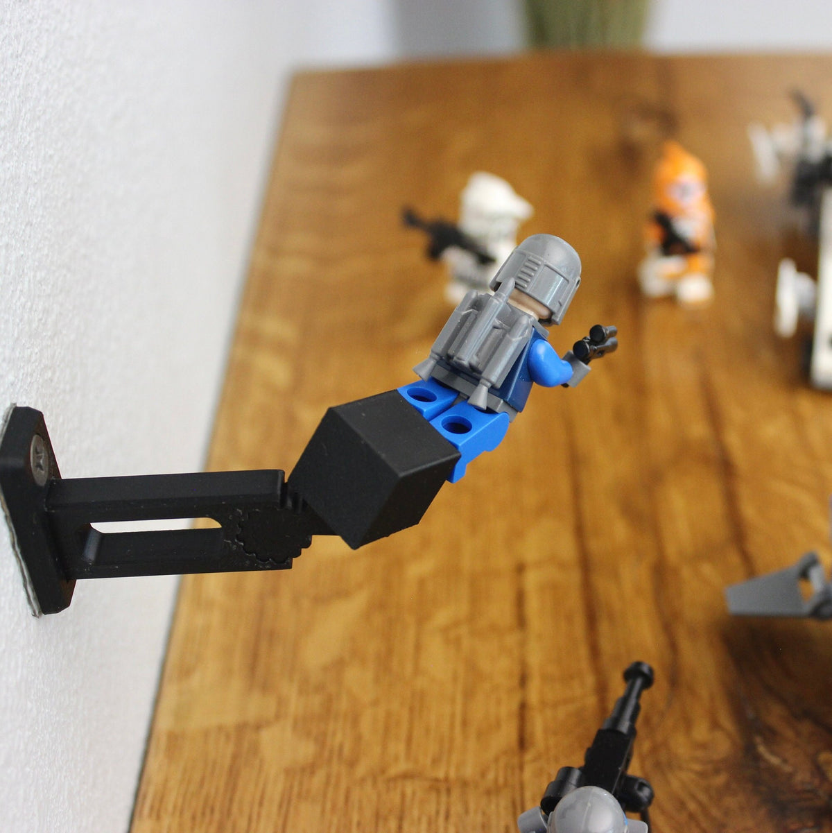 Small LEGO vehicle held out from a wall by the short black universal wall mount above a wooden shelf