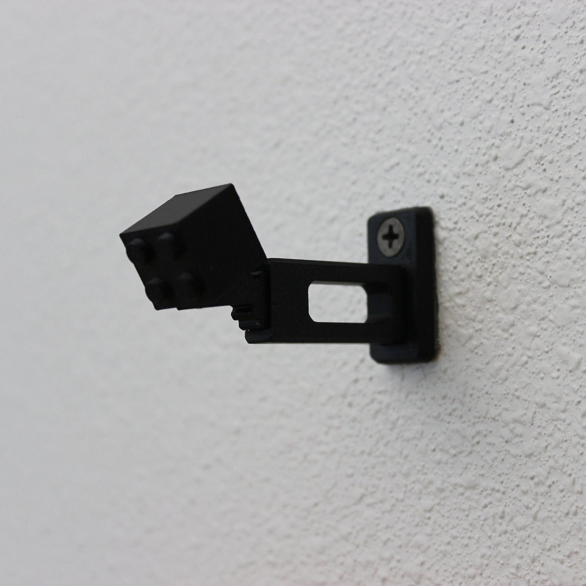Short black universal wall mount on a white wall, seen from below